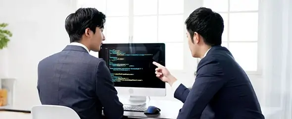 先輩ITエンジニアが新卒学生にプログラミングを教えている